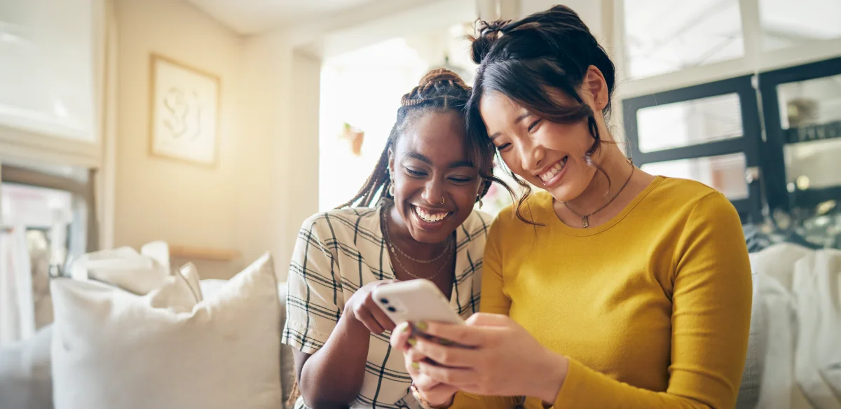 Two student smiling while looking at their cellphone