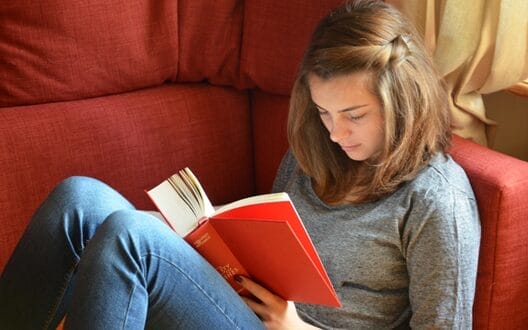 female student reading on a sofa